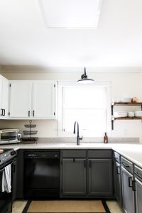gray lower cabinets with farmhouse light over sink