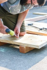 man using impact driver to screw 2 pieces of boards together