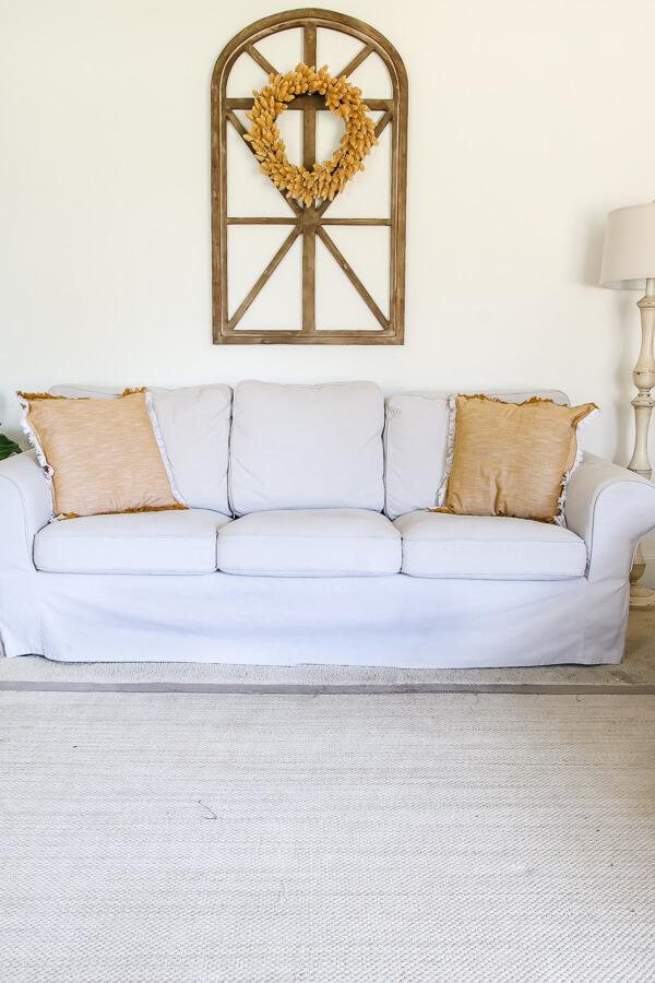 Ikea Ektorp sofa against wall with Sherwin Williams Alabaster with mustard color throw pillows