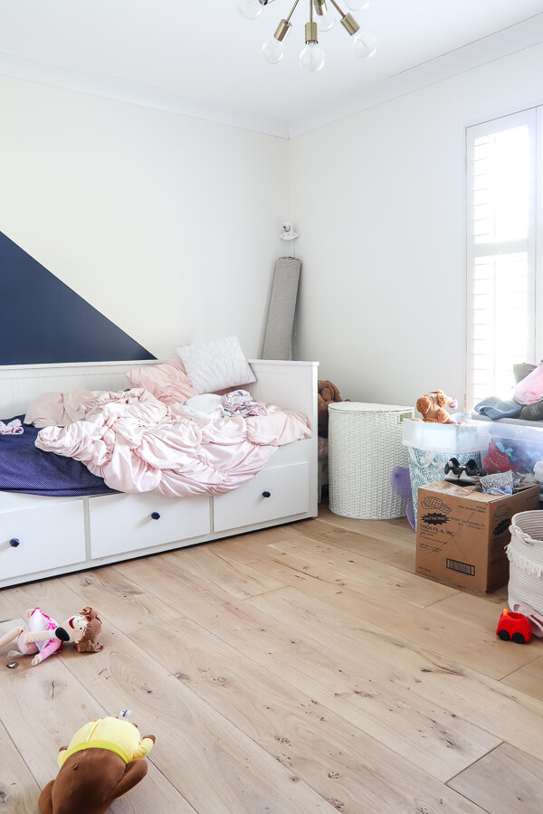 messy little girl's room with wood floors and Ikea bed in Sherwin Williams Alabaster white