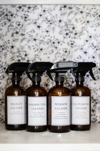 4 DIY homemade cleaners in amber bottles with flower background