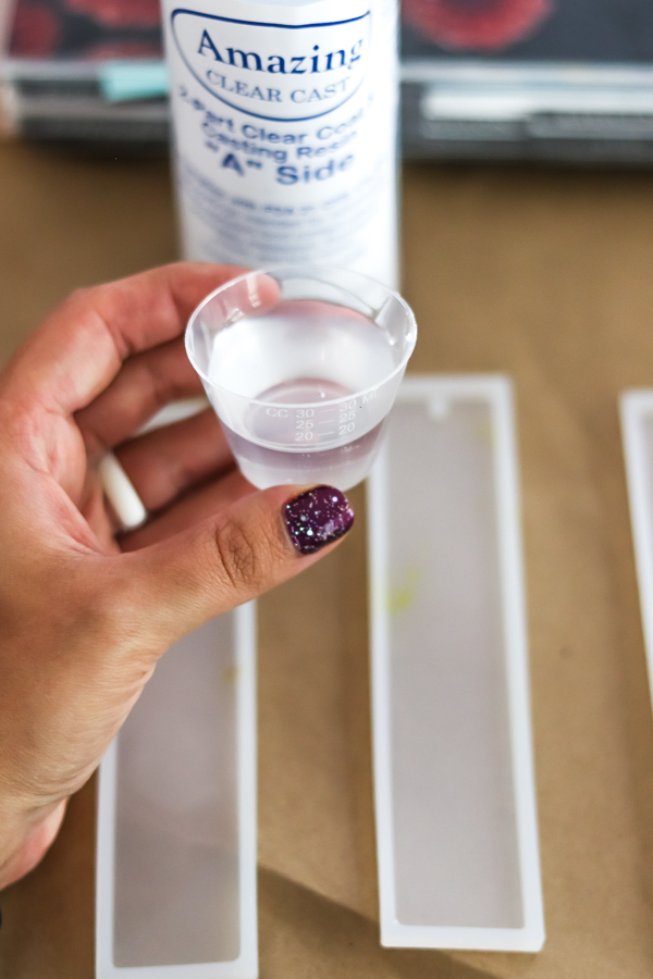 woman's hand holding measuring cup of resin