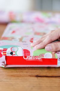 woman's hand folding ends of wrapping paper on box