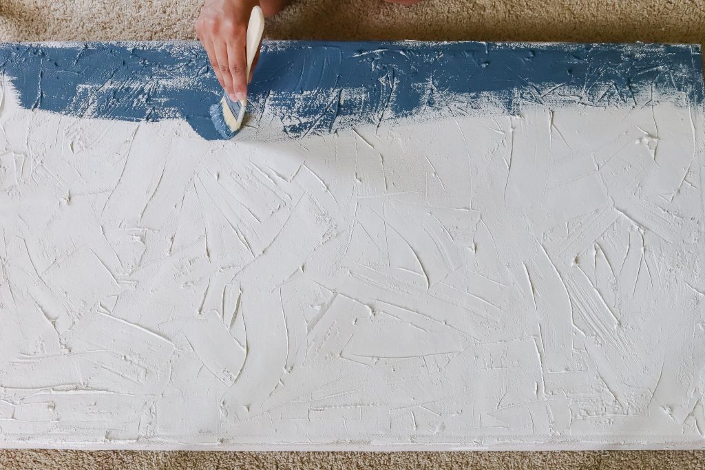 woman's hand painting navy on textured canvas abstract art