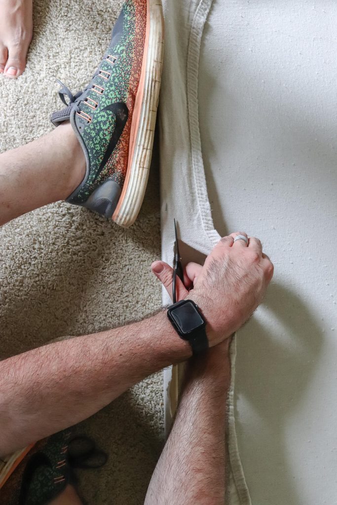 man cutting excess canvas from wood frame for DIY abstract canvas art