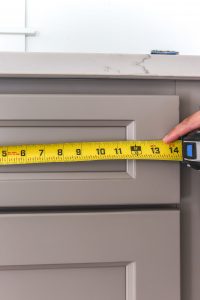 yellow tape measure on greige kitchen cabinets