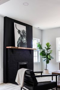 black fireplace painted Sherwin Williams Tricorn Black and cow painting over live edge mantle