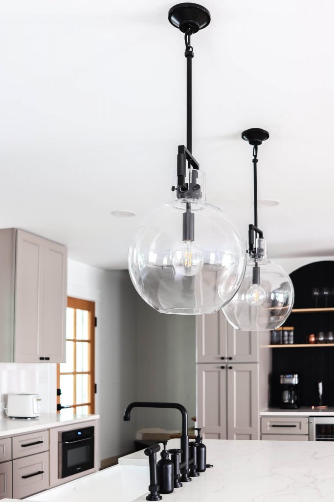 black pendant lights with glass globes over island
