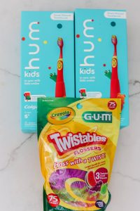 twistables flossers and colgate hum toothbrushes laying down on white quartz countertops