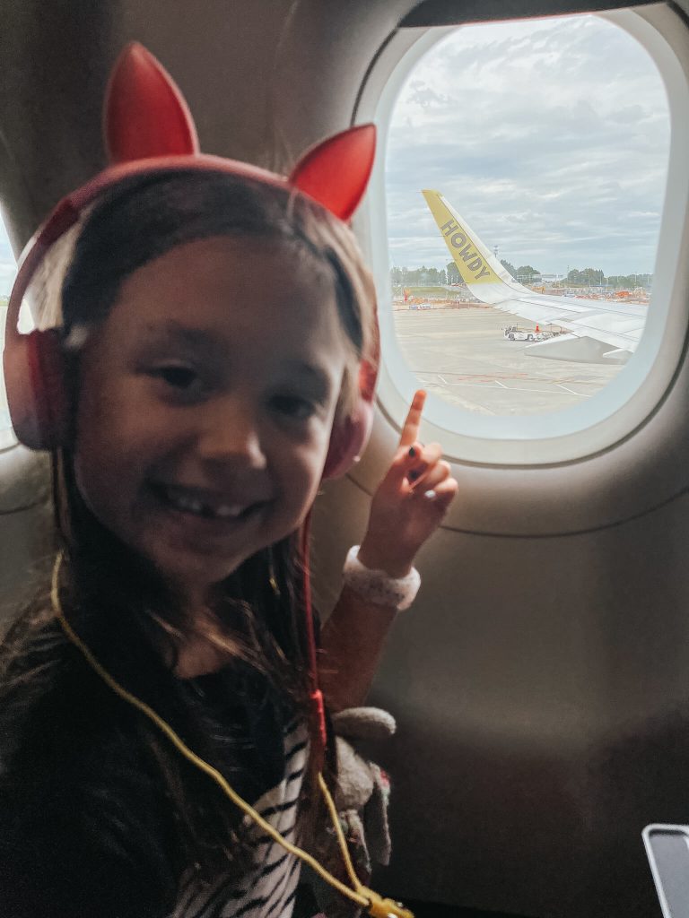 girl in cat headphones pointing out the window of an airplane