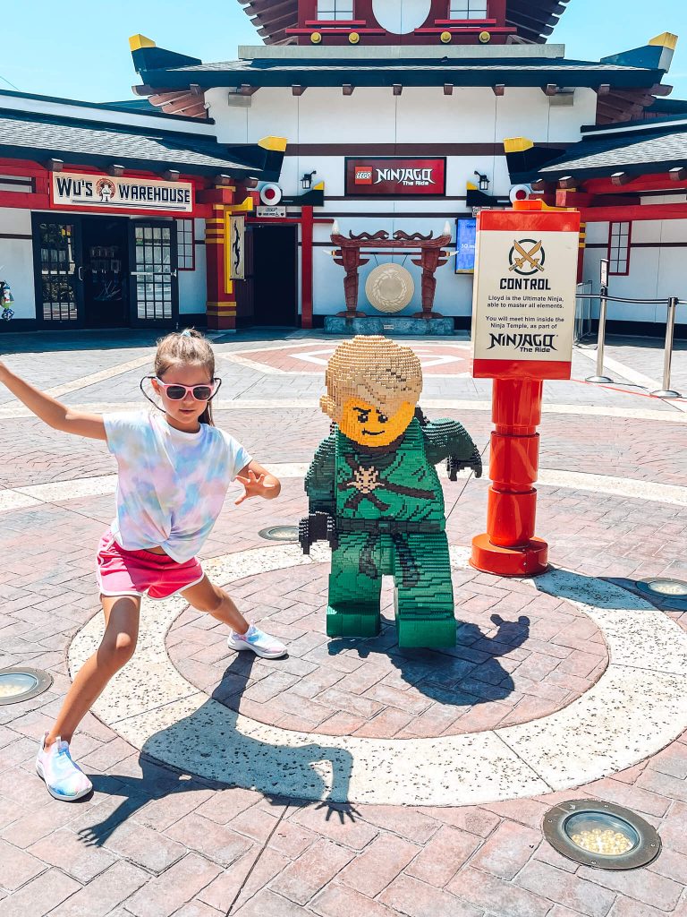 little girl making ninja pose in front of Ninjago world at Legoland florida