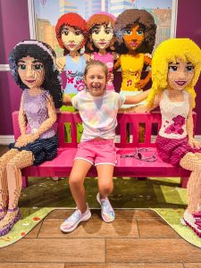 girl sitting with lego friends characters on bench at Legoland florida