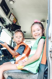 little girl and toddler boy in trash truck making silly faces