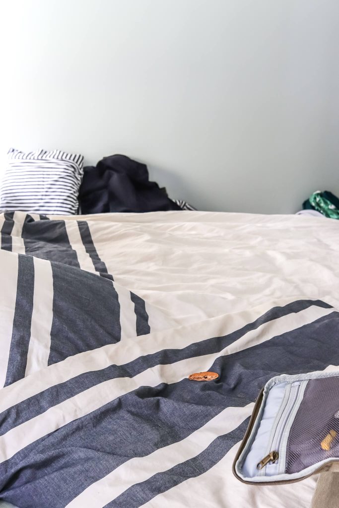 white and gray stripe bedding on bed with cookie on bed