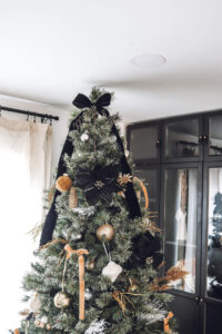 closeup of top of Christmas tree with black flower and black ribbon tied at top