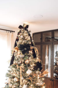 closeup of top of Christmas tree with black flower and black ribbon tied at top