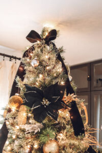 closeup of top of Christmas tree with black flower and black ribbon tied at top