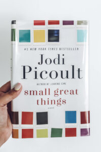 womans hand holding Small Great Things book by Jodi Picoult