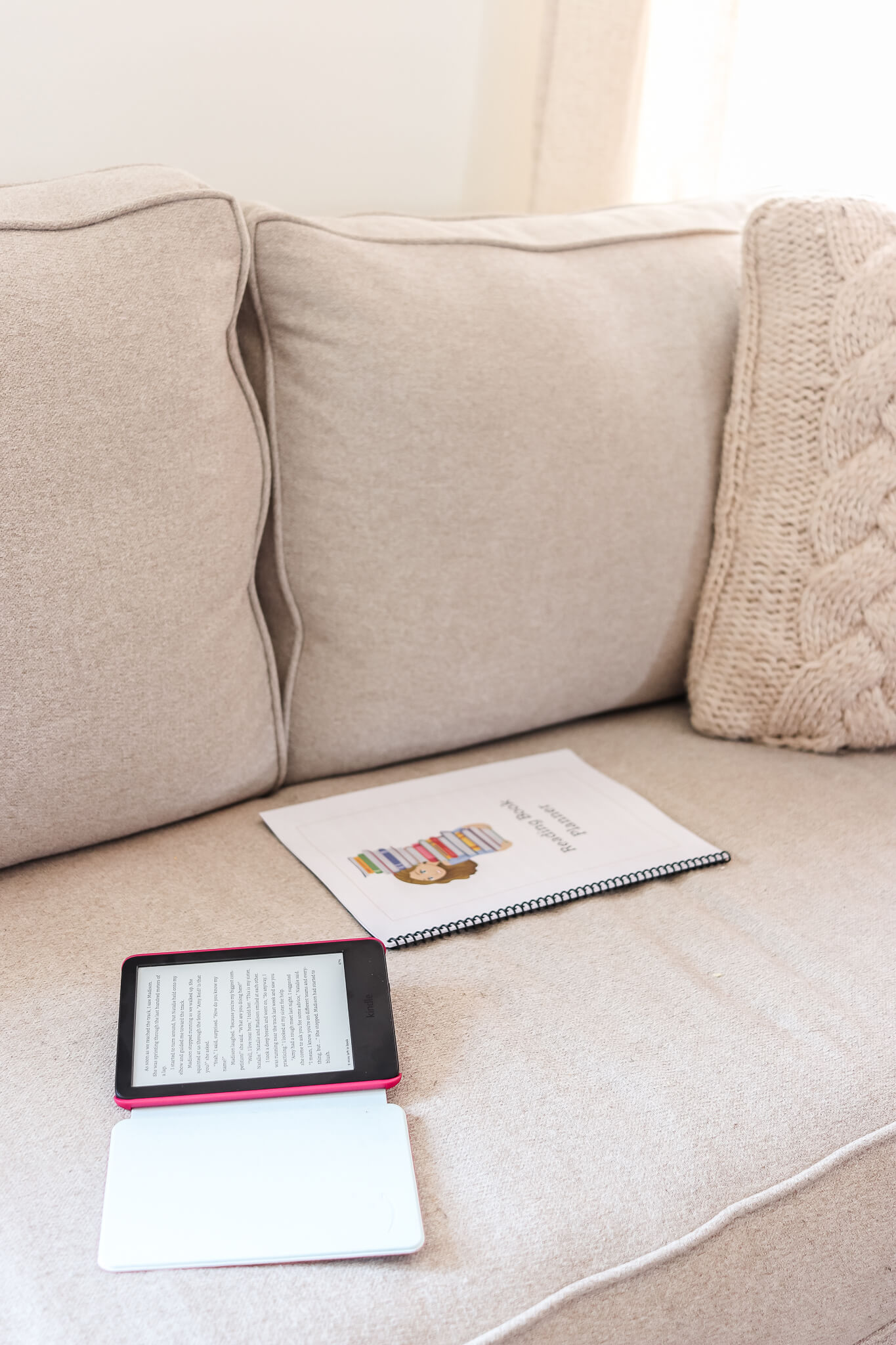 kindle for kids laying on couch next to reading log free printable