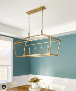 dining room with brass chandelier and benjamin moore aegean teal painted on top half of wall