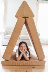 little girl with her hands under her chin sitting in a nugget house