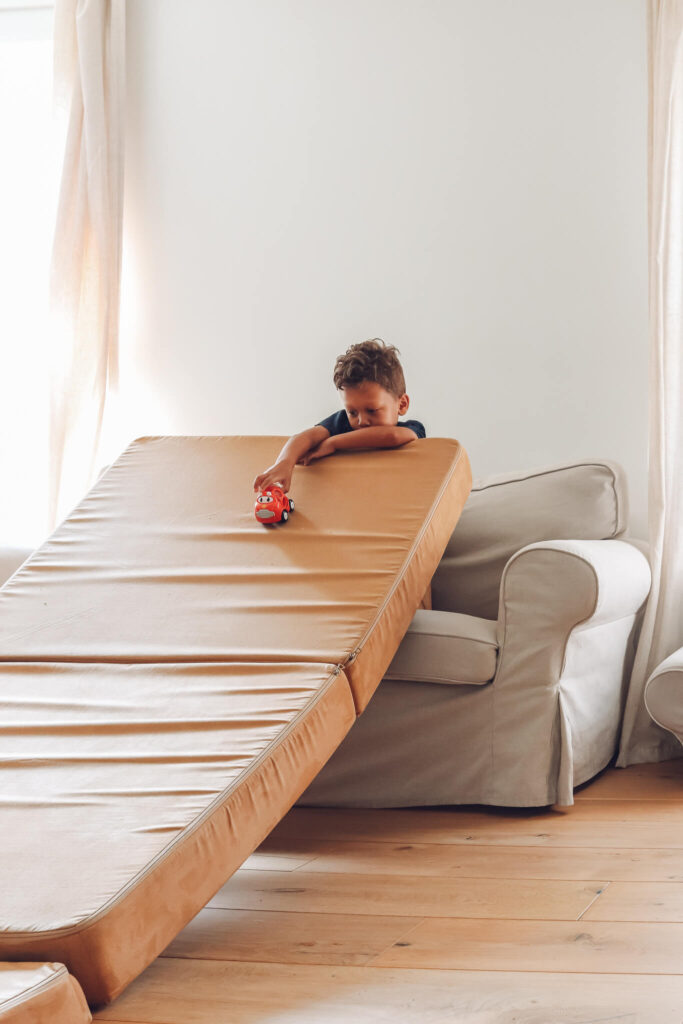 little boy rolling toy car down nugget couch