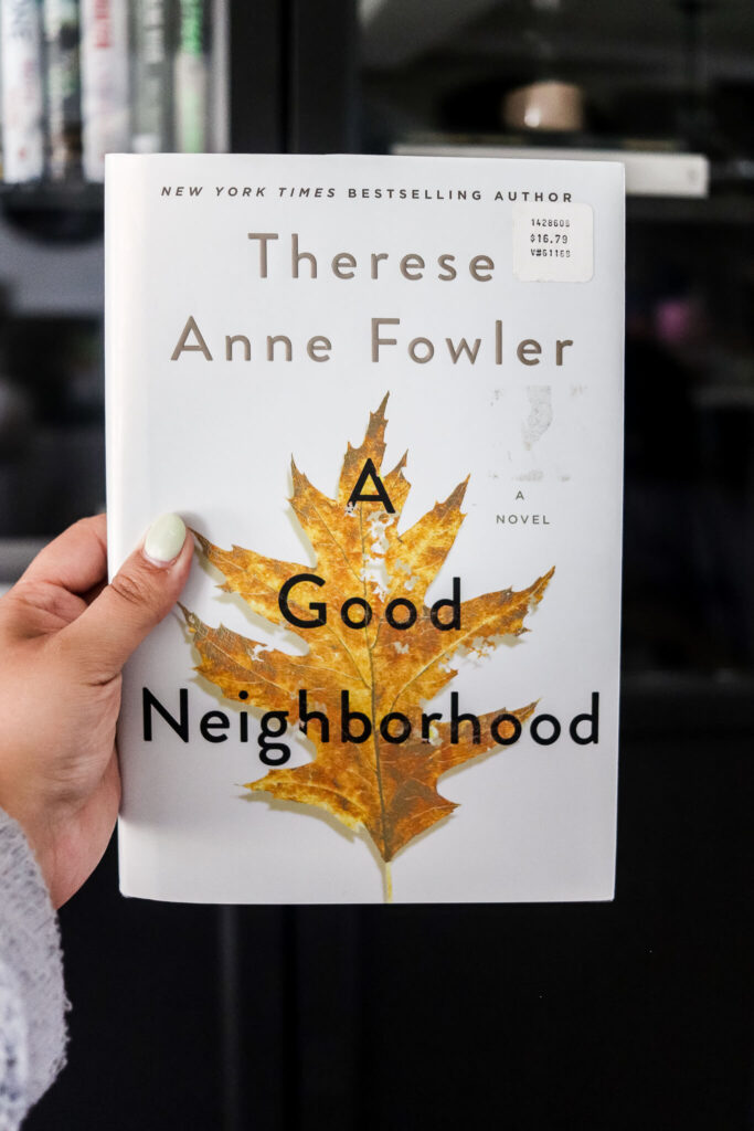 woman's hand holding a good neighborhood by therese anne fowler