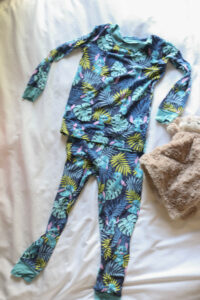 little sleepies bamboo lilo and stitch pajamas for kids laying on bed next to lovey
