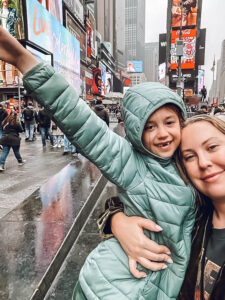 woman and little girl holding her arm up in Times Square