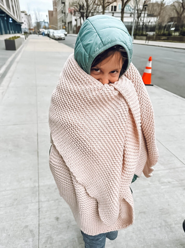 little girl in teal jacket with pink blanket wrapped around her