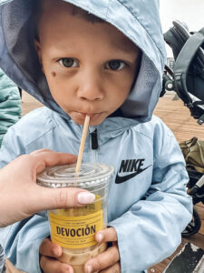 toddler boy drinking iced coffee with gray jacket and hood up