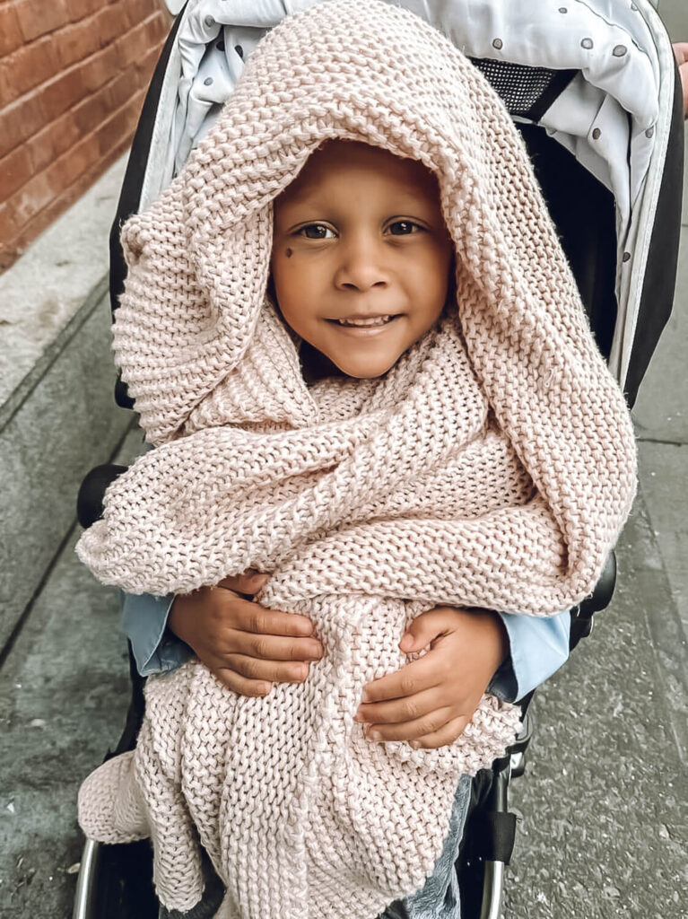 little boy with pink blanket wrapped around him in stroller