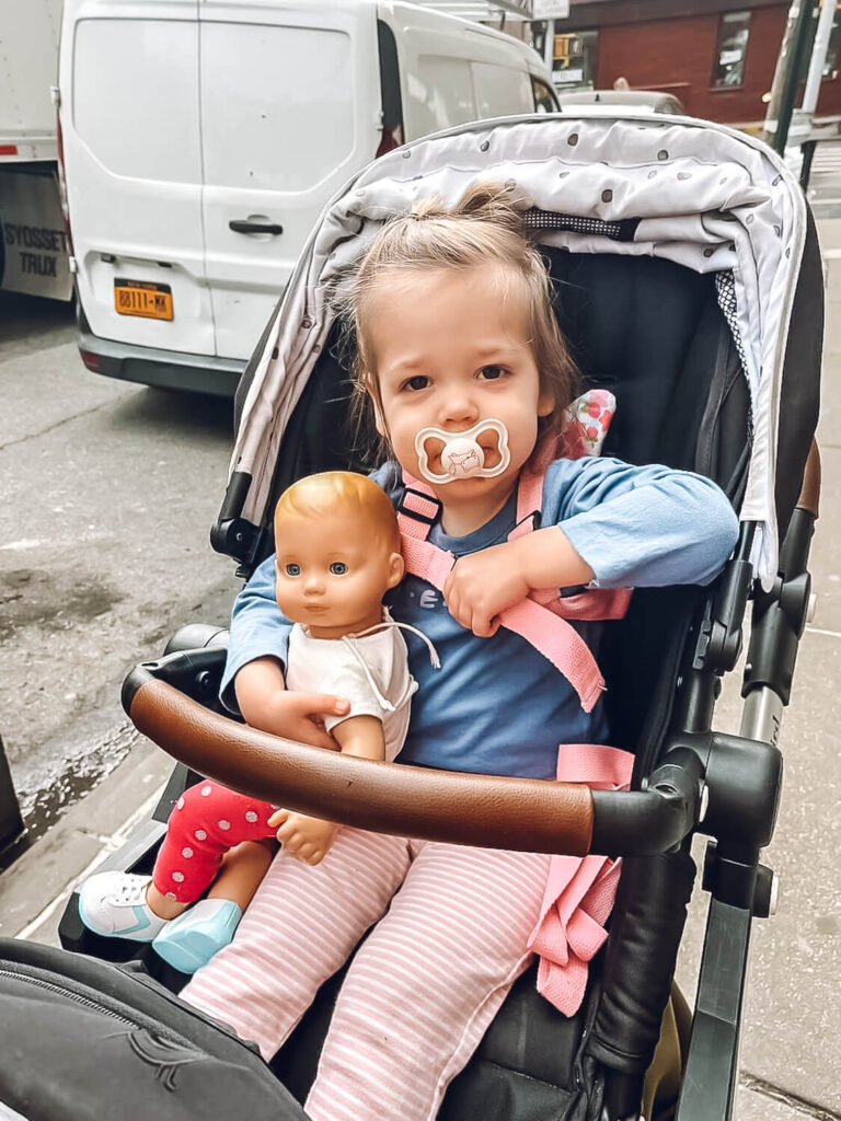 little girl holding American Girl doll bitty baby in double stroller
