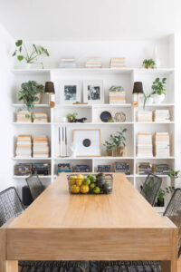 brown kitchen table with stacked books on organized bookshelves