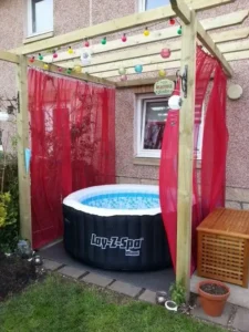 inflatable hot tub on deck with colorful sheer curtains and colorful balls hanging from pergola