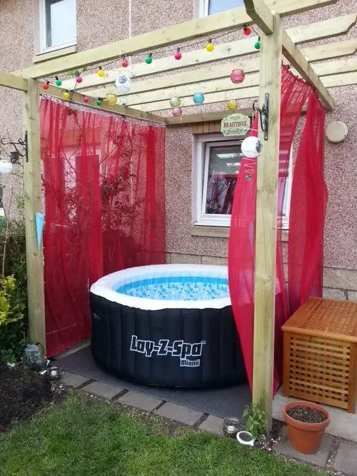 inflatable hot tub on deck with colorful sheer curtains and colorful balls hanging from pergola