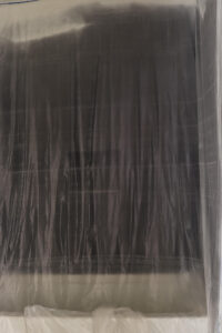 painters plastic in bathroom covering black tile and white tub