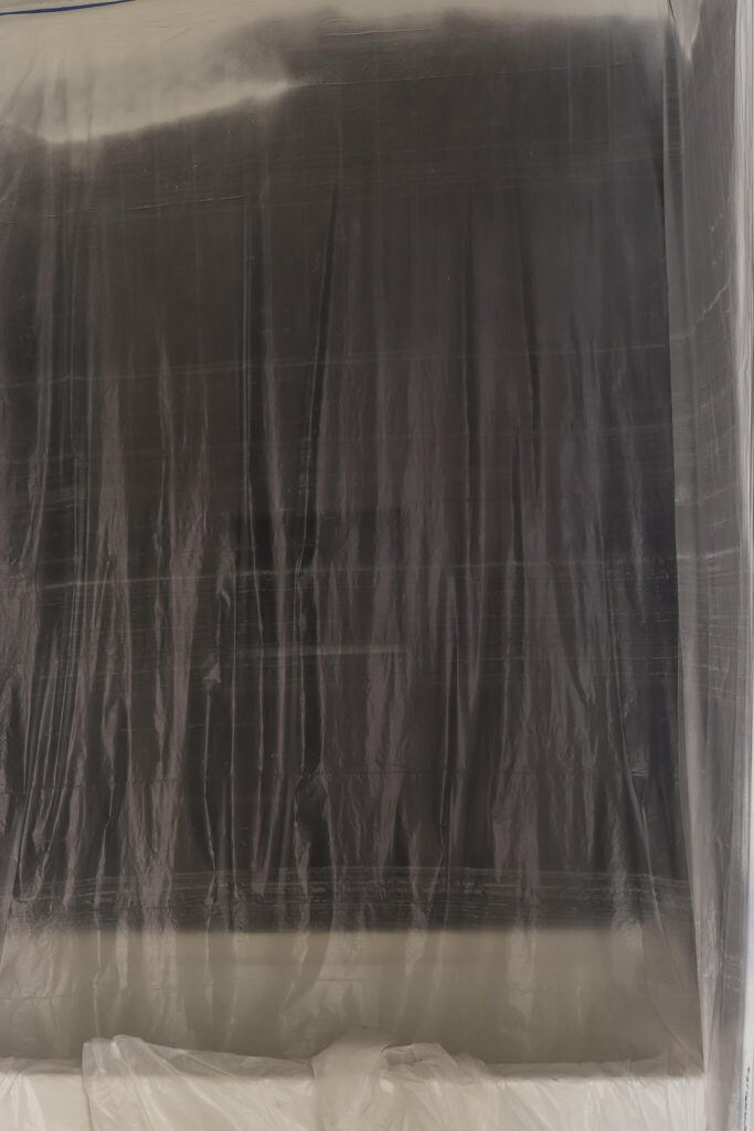 painters plastic in bathroom covering black tile and white tub