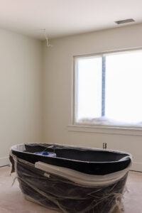 black soaker tub in an unfinished room with white walls