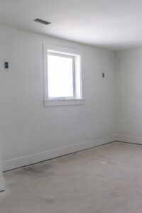 bedroom with white walls and unfinished flooring
