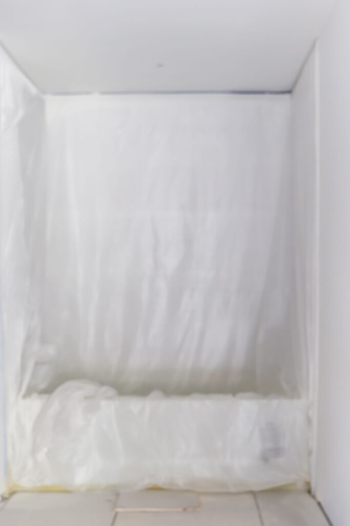 painters plastic covering white tile in bathroom