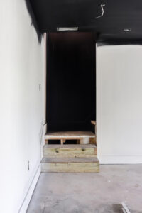 wood unfinished stairs with black shiplap accent wall