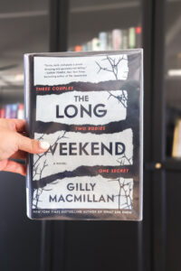 woman's hand holding the long weekend by gilly macmillan