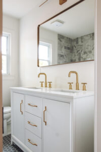 closeup of white vanity in bathroom with gold faucet and vanity hardware