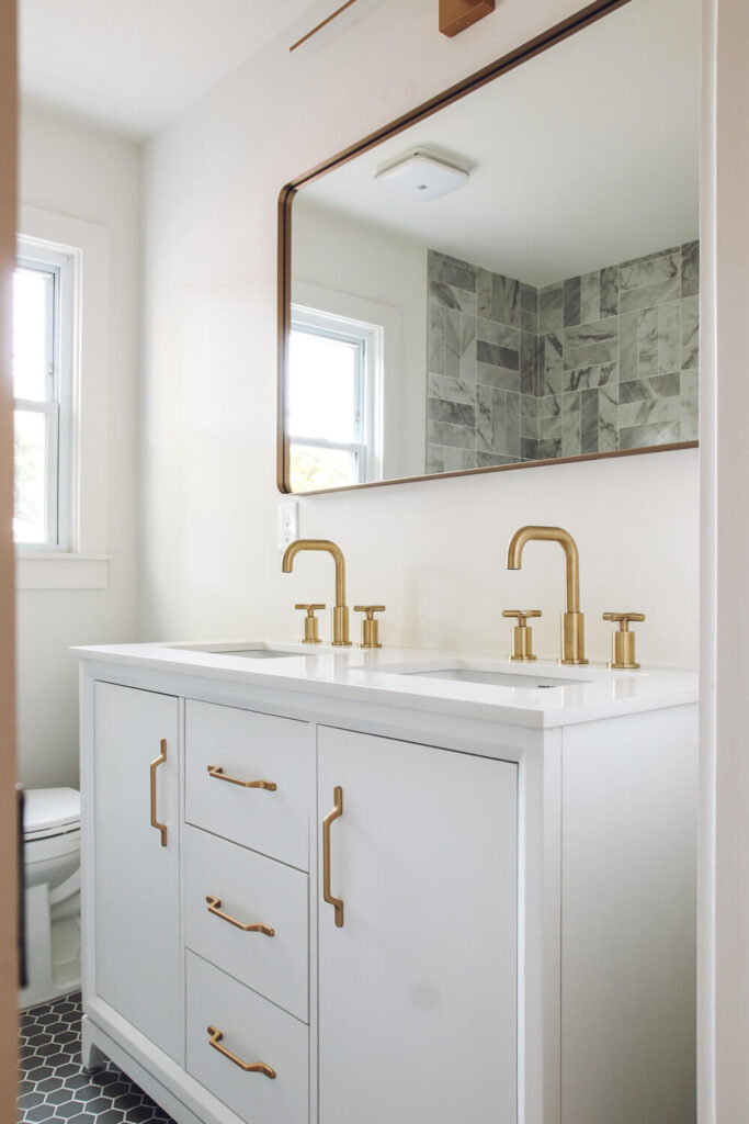 closeup of white vanity in bathroom with gold faucet and vanity hardware
