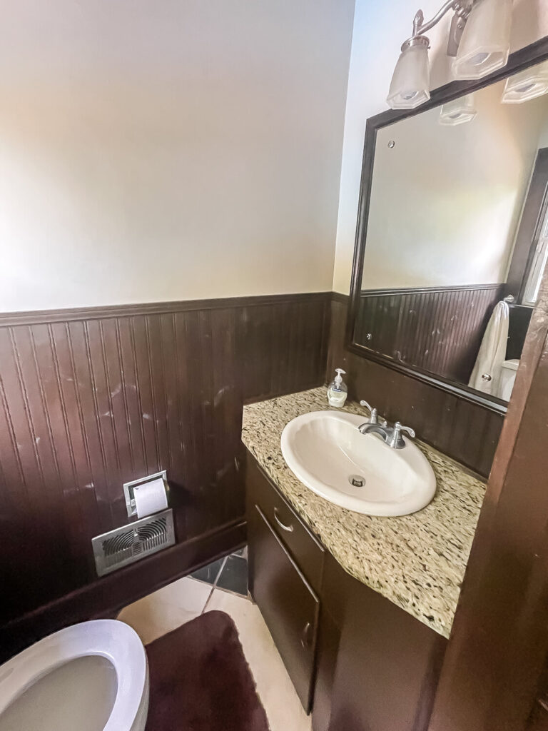 old bathroom with brown beadboard and granite vanity with white sink