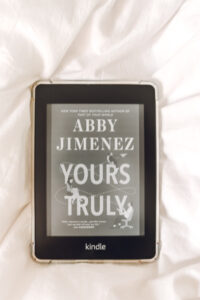 yours truly abby jimenez cover on kindle laying on white covers