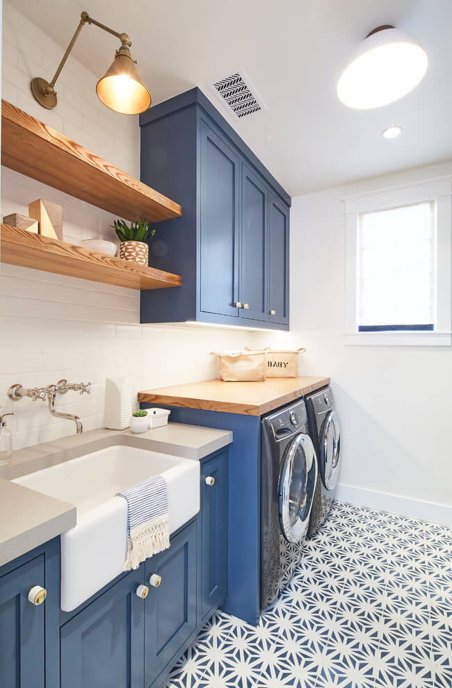 blue painted cabinets in laundry room and wooden shelves over laundry room sink