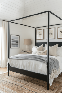 black canopy bed with simple bedding and 3 pictures hanging above the bed