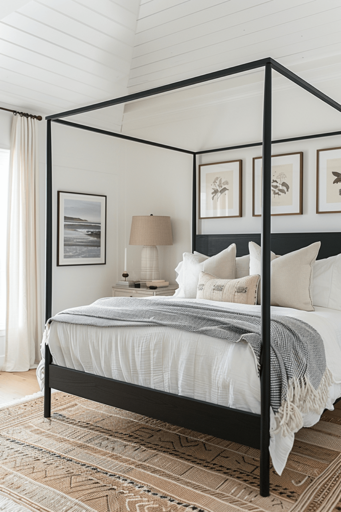 black canopy bed with simple bedding and 3 pictures hanging above the bed